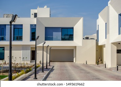 White and blue modern villas in a Middle Eastern, high-end, luxury housing development on a sunny day with strong shadows.