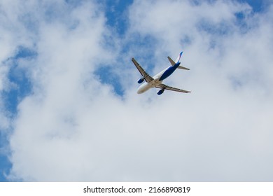 White- blue passenger airplane flying in the sky amazing clouds in the background , travel by air transport, population evacuation.