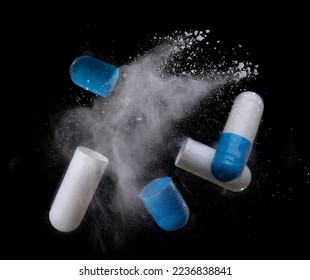 white and blue pill with exploding over a black background,Concept of medicine