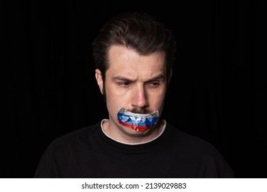 White, Blue And Red. Conceptual Portrait Of Young Man With Three Colors Duct Tape Over His Mouth Isolated On Dark Background. Censorship, Freedom Of Speech Concept.