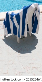 White And Blue Striped Towel On A Plastic Chair By A Pool