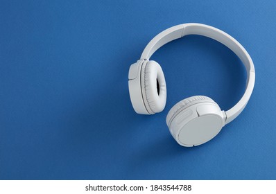 White bluetooth headphones on blue background