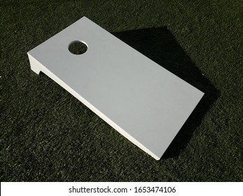 white board with hole for beanbag toss on grass