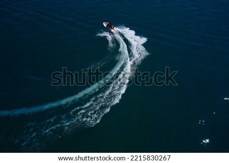 White boat in motion entering a turn on dark water top view.