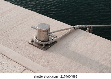 white boat rope tied to marina pier bollard, white shore line