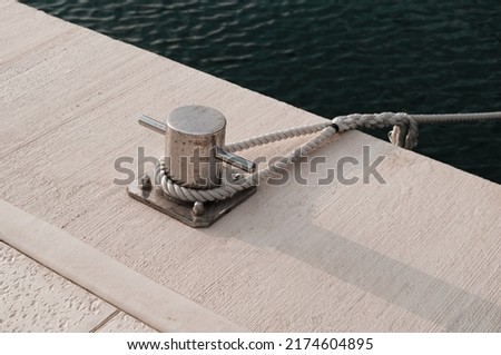 white boat rope tied to marina pier bollard, white shore line