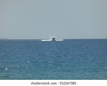 A White Boat Sails Right At Us On The Waters Of Ibiza With A Clear Blue Sky