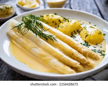  White boiled asparagus in hollandaise sauce with potato puree served on wooden black table 