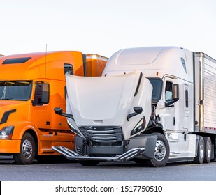 White Bonnet Big Rig Semi Truck With Open Hood For Engine Inspection And Possible Mobile Repair Standing On The Truck Stop Parking Lot On Row With Another Semi Trucks