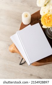 White Book Blank Cover Mockup On Stylish Wooden Coffee Table With Roses Bouquet, High Angle View