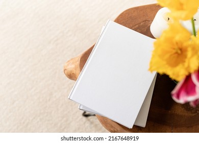 White Book Blank Cover Mockup On Stylish Wooden Coffee Table With Tulips Bouquet, High Angle View