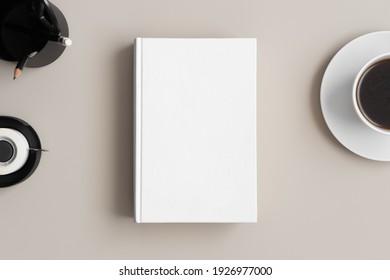 White Book Mockup With A Coffee And Workspace Accessories On A Beige Table.