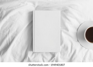 White Book Mockup With A Cup Of Coffee On The Bed.