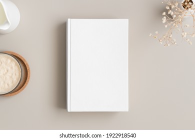 White Book Mockup With A Gypsophila, Coffee And A Bottle Of A Milk On A Beige Table.