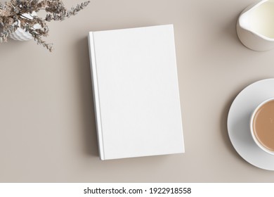 White book mockup with a lavender, coffee and a bottle of a milk on a beige table.