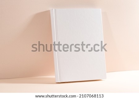 White book mockup on a beige table.