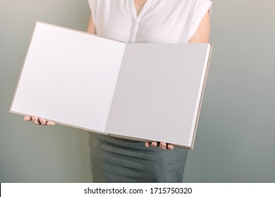 White Book Mockup In Woman's Hands. Woman In Office Outfit Holding The Opened Book With Clean White Pages. White Blank Book Inside. Album Mockup.