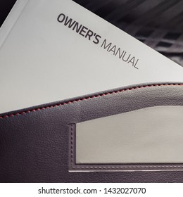 A white book placed in all new vehicles called an owner's manual usually placed in a black leather pouch located inside the glove compartment.  - Shutterstock ID 1432027070