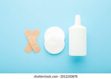 White Bottle Of Hydrogen Peroxide, Cleansing Cotton Pads And Adhesive Bandages On Light Blue Table Background. Pastel Color. Medical Kit For Skin Wound Cleaning. 