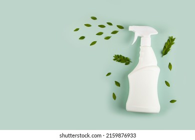 White bottle mockup for cleaning. Eco spray bottle for safe cleaning with green leaves on green background. Copy space, flat lay. 
