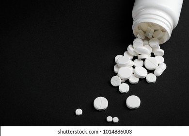 White Bottle And Spilled Tablets On Black Table. Overdose By Sleeping Pills. Suicide Attempt Concept.