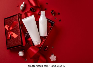 White bottles cosmetic products in red giftbox and on red background. Christmas sale of beauty products concept. Top view with place for text.