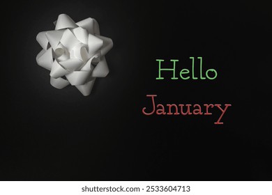 White bow is on a black background with the words Hello January written in red and green - Powered by Shutterstock