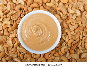 White Bowl With Fresh Cashew Butter Surrounded By Cashew Nuts. Cashews Are A Good Source Of Plant Protein, Contain No Cholesterol And Are Low In Saturated Fat.