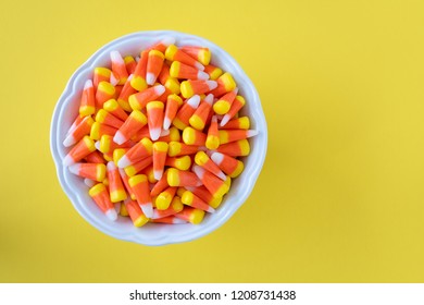 White Bowl Full Of Halloween Candy Corn On A Yellow Background
