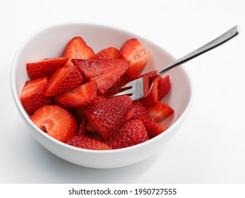 White Bowl Full Of Sliced Strawberries With Fork On White Background