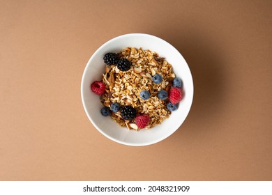 White Bowl With Granola And Fresh Berries Overhead View On Brown Surface Healthy Breakfast