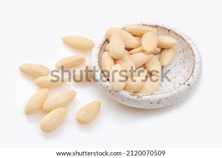 White bowl of peeled or blanched almonds on white background.  Shallow depth of field