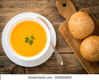 white bowl of pumpkin soup, garnished with parsley on wooden background, top view. - Powered by Shutterstock