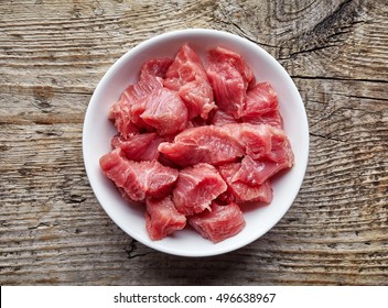 White Bowl Of Raw Diced Beef Meat On Wooden Table, Top View