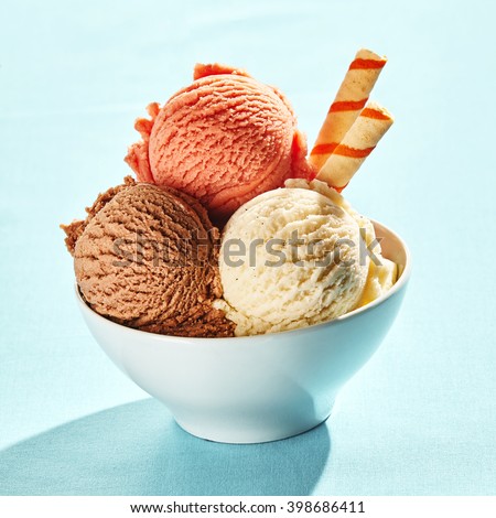 White bowl topped with trio of homemade creamy italian frozen dessert against a blue background