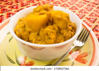 A White Bowl Of Yam And Beans Pottage Or Nigerian Porridge Served On A Plate With A Colorful Red Pattern African Tablecloth