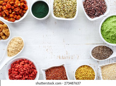 White bowls of various superfoods on white wooden  background
