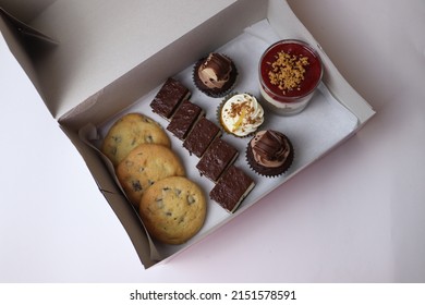 White box with pastry sweets cookies with chocolate kinder milk slice muffins orange carrot cake cheesecake