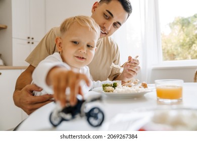 White boy playing with toy while having breakfast with his son at home