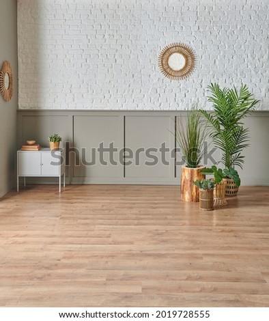 White brick and classic brown pattern on the wall, gold vase of plant, grey cabinet, mirror, brown parquet floor.