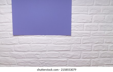 White brick wall. The background is white. White bricks with purple paper with copy space