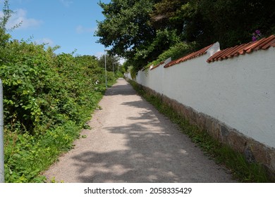 White Brick Wall By A Narrow Uphill Path.