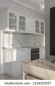 White bright kitchen in a modern style with an apron of white marble and household appliances