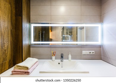 White And Brown Bathroom Boasts A Nook Filled With Double Vanity Cabinet Topped With White And Grey Counter Paired With Tile Backsplash Under Framed Mirror