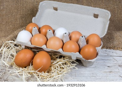 White And Brown Chicken Eggs On A Wood Shavings And In Egg Carton Made Of Recycled Paper Pulp On An Old Wooden Surface With Sackcloth, Close-up  
