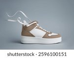 White brown sneacker closeup.Fashion shoe, leather womens sneakers isolated on gray background. Fashionable stylish sports casual shoes, minimalistic layout with footwear, shoe store advertisement.