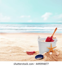White Bucket With Red Shovel And Rake On Clean Empty Beach Near Beautiful Ocean On A Pleasant Day