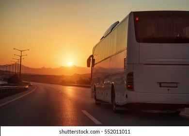 White bus driving on road towards the setting sun - Shutterstock ID 552011011