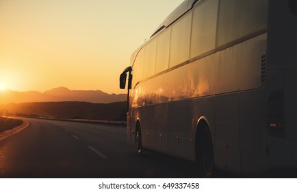 White bus driving on road towards the setting sun - Shutterstock ID 649337458