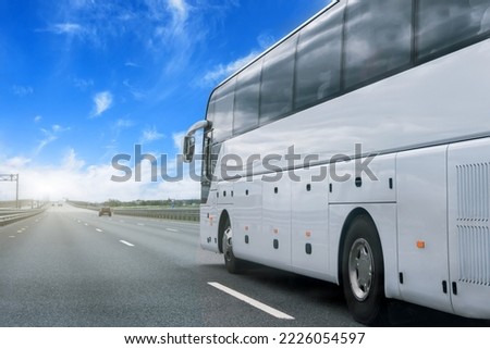 White bus on asphalt road on sunny day, partly cloudy sky in the countryside